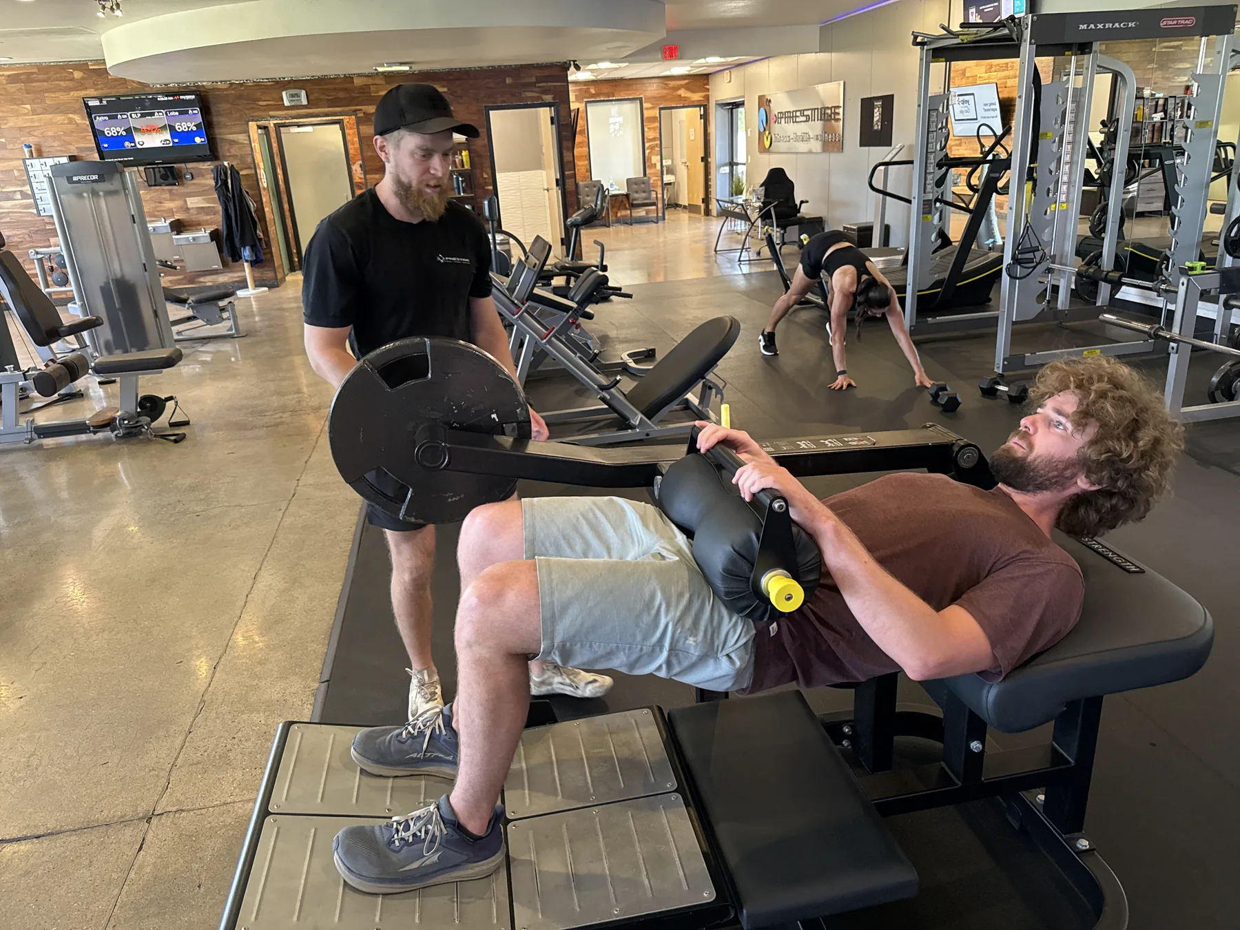 A Prestige coach spotting a client on the bench at the midtown Tucson gym