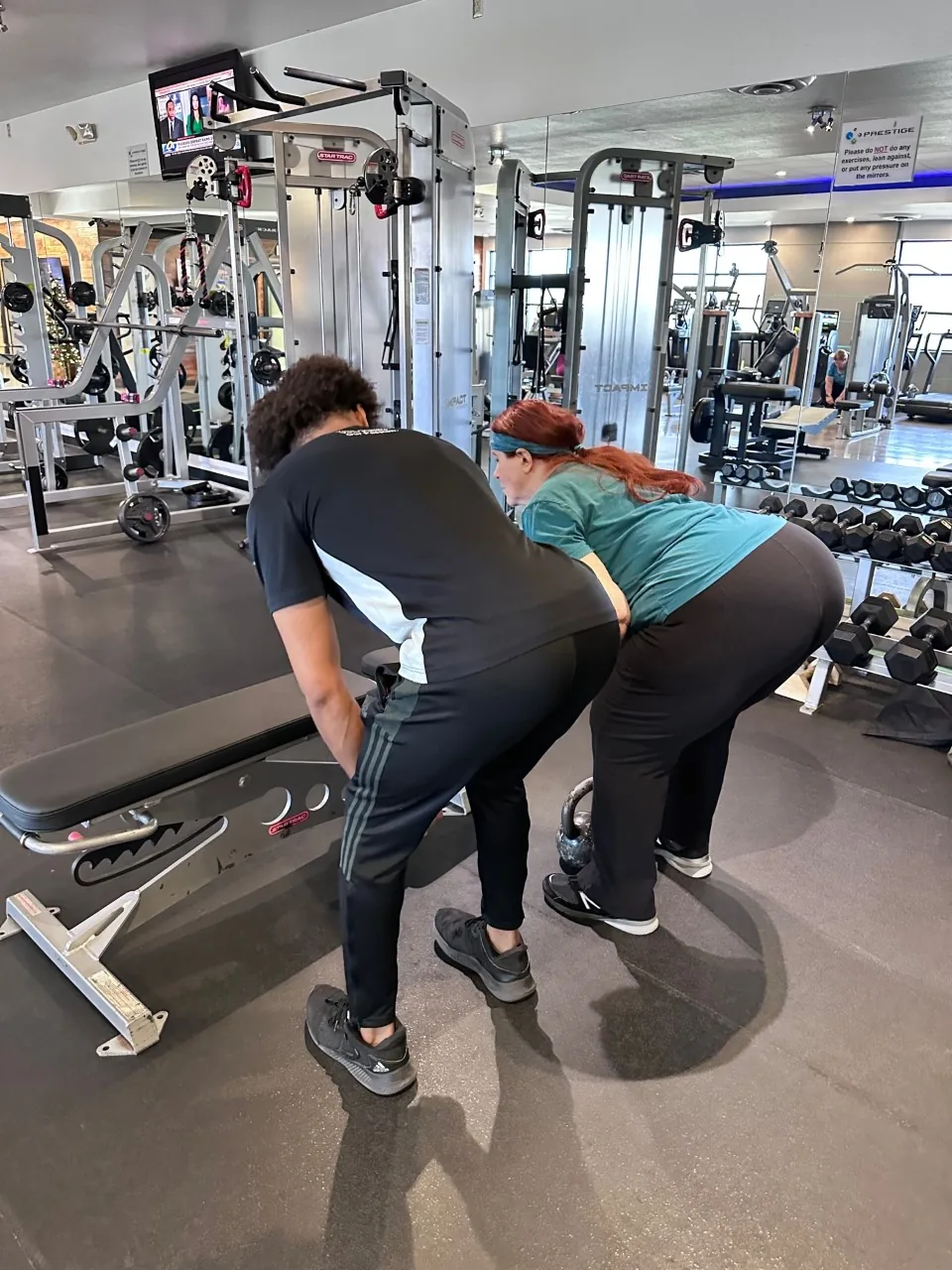 A Prestige coach cueing a client through a strength exercise on the Tucson training floor