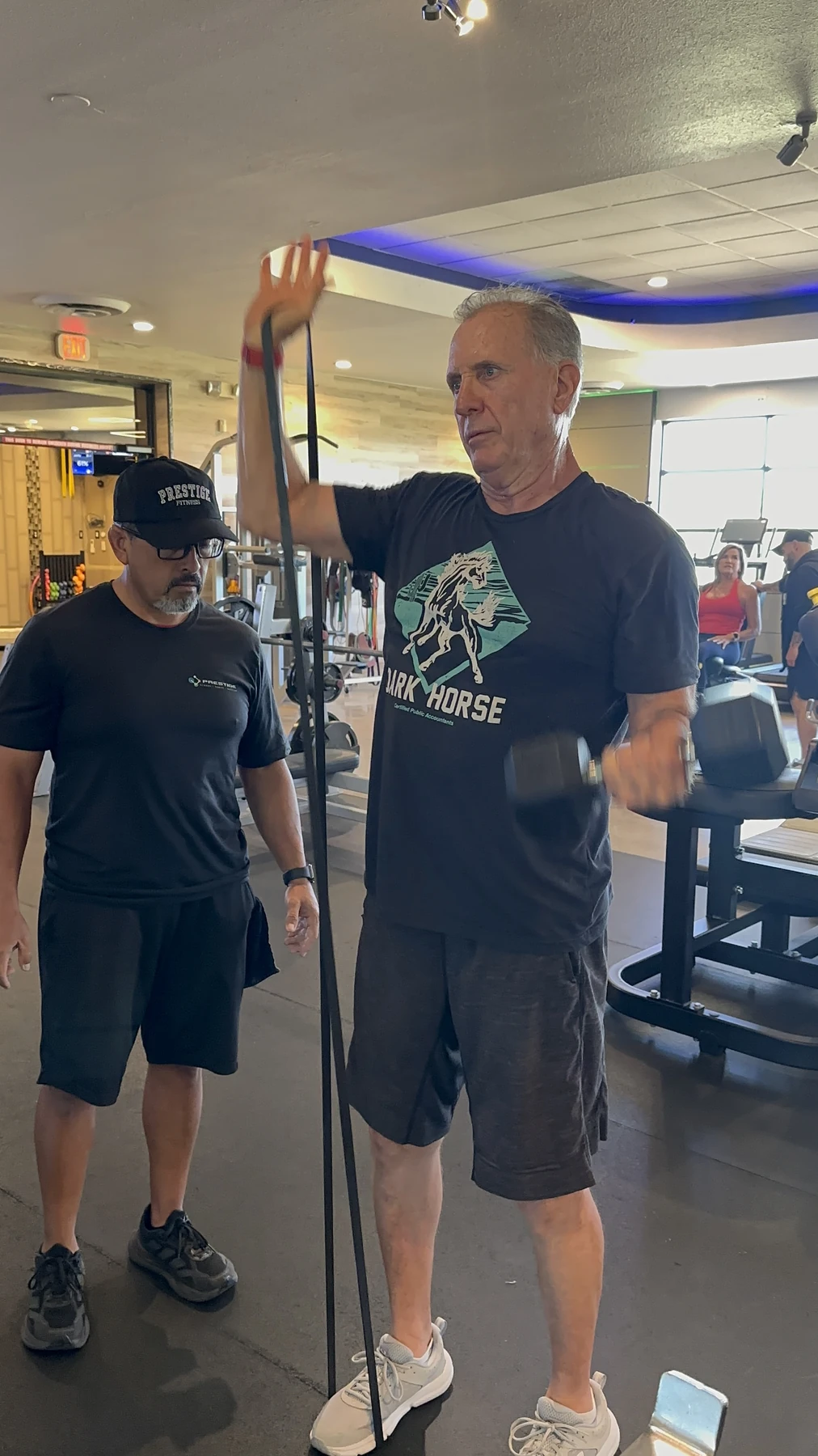 Adult client training with his Prestige coach - band and dumbbell work on the Tucson floor