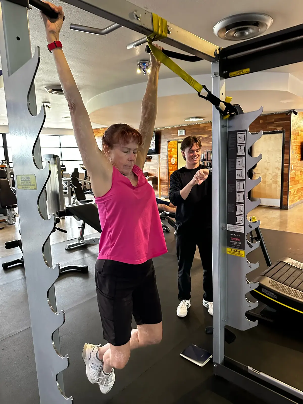 Adult client on an assisted pull-up with her Prestige coach in Tucson