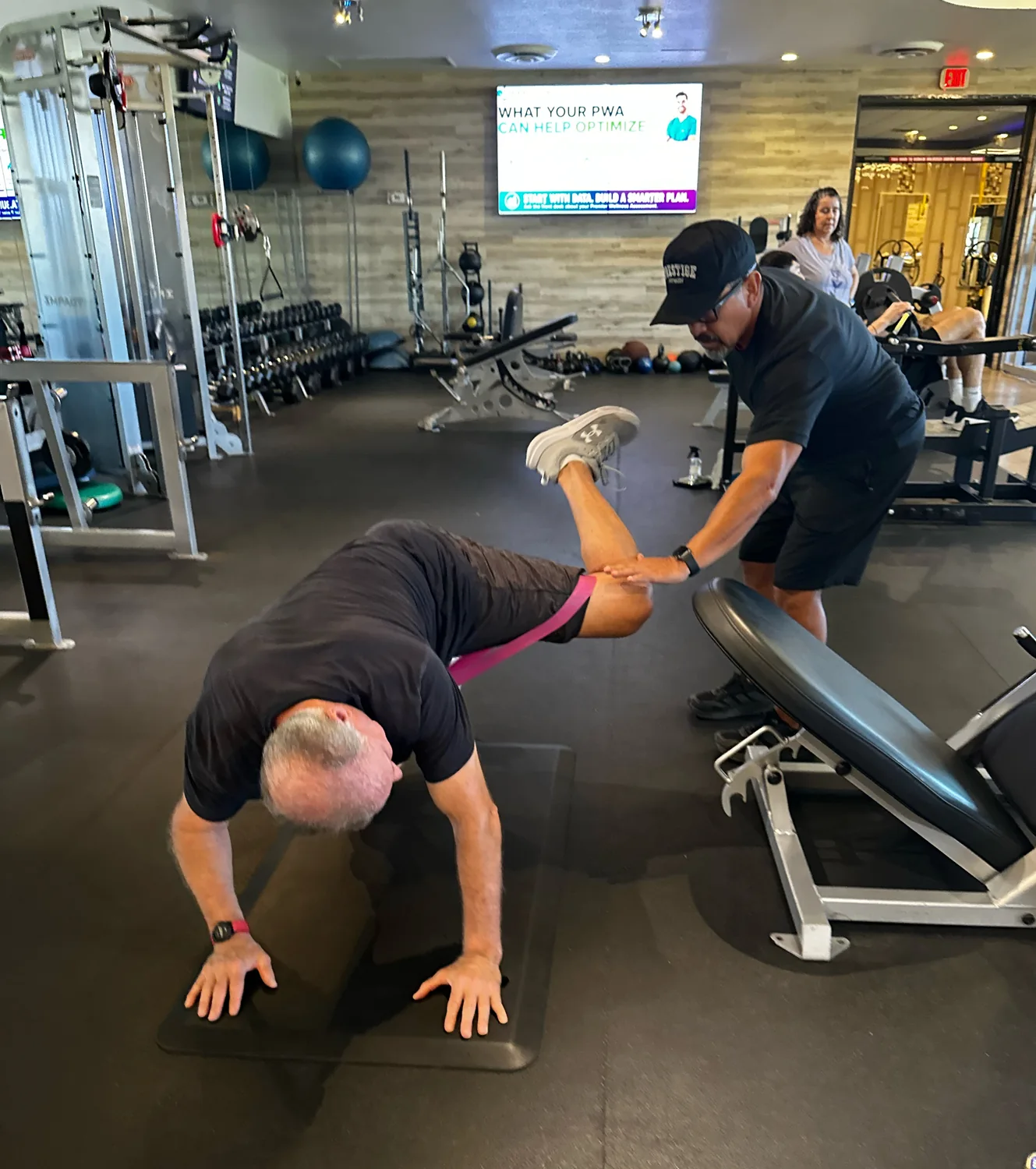 Adult client coached through a banded plank progression with his Prestige trainer in Tucson